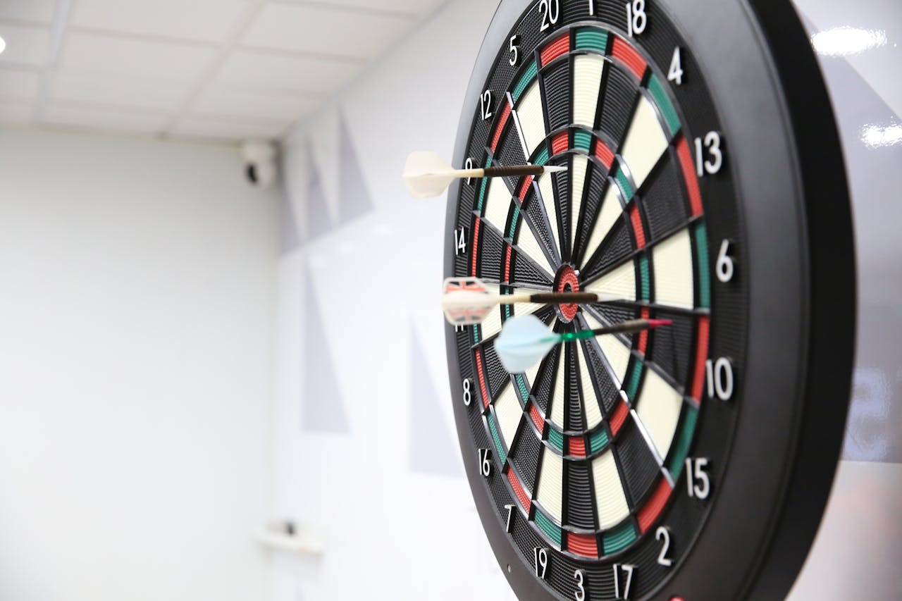 A precise shot on a dartboard capturing two darts hitting the target indoors.