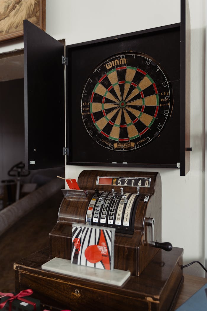A classic setup featuring a vintage dartboard and an antique cash register inside a store setting.
